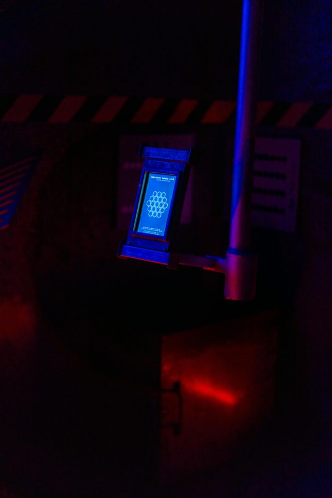 A dimly lit futuristic control panel with a blue screen in a sci-fi setting, displaying an abstract design.