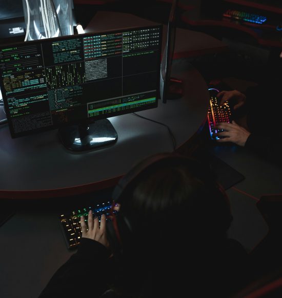 A group of people in a dark room working on computers, related to cybersecurity.