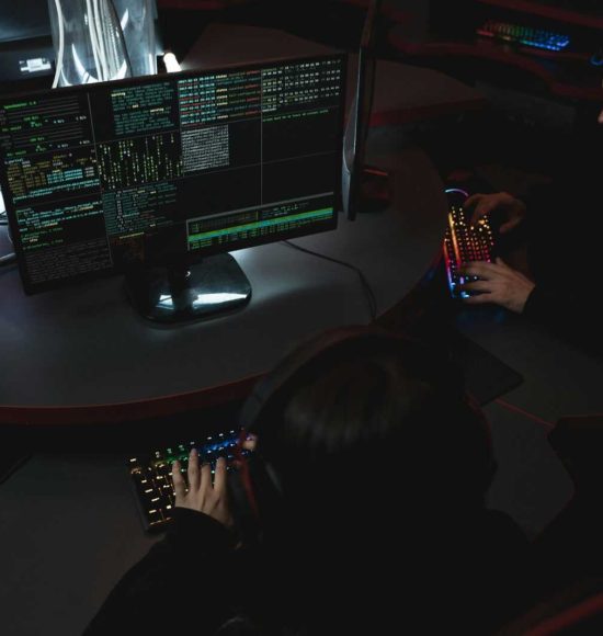 A group of people in a dark room working on computers, related to cybersecurity.