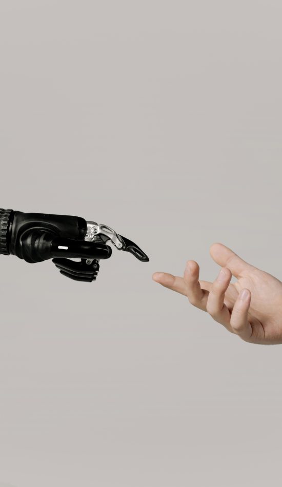 A human hand reaching to touch a bionic prosthetic hand on a white background.