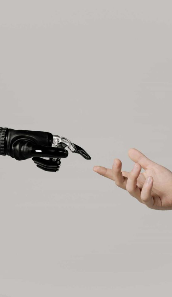 A human hand reaching to touch a bionic prosthetic hand on a white background.