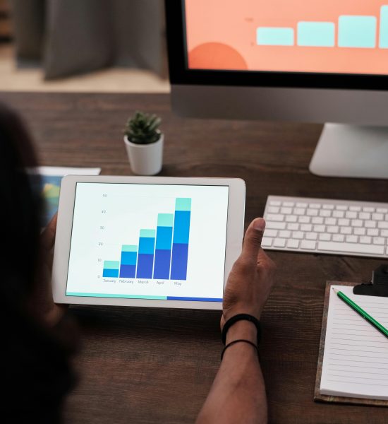 A person reviews statistical graphs on a tablet, showcasing data analysis and technology.