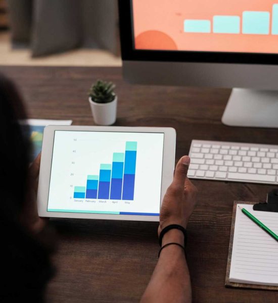 A person reviews statistical graphs on a tablet, showcasing data analysis and technology.