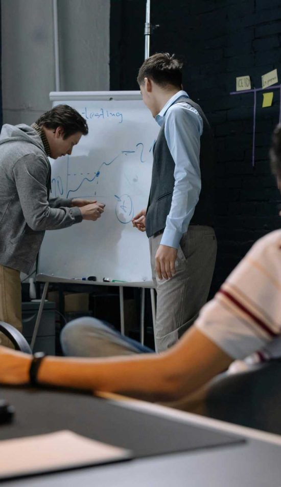 Group of adults engaging in creative brainstorming session around a whiteboard in modern office.