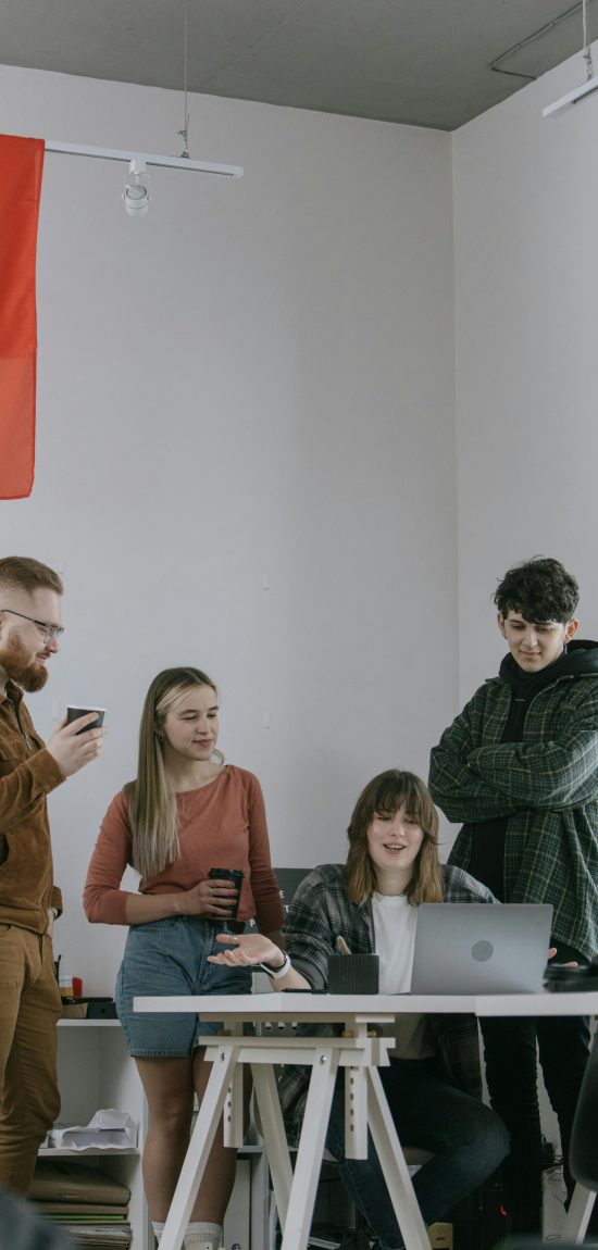 A group of young professionals engaged in a collaborative meeting in a modern office setting.