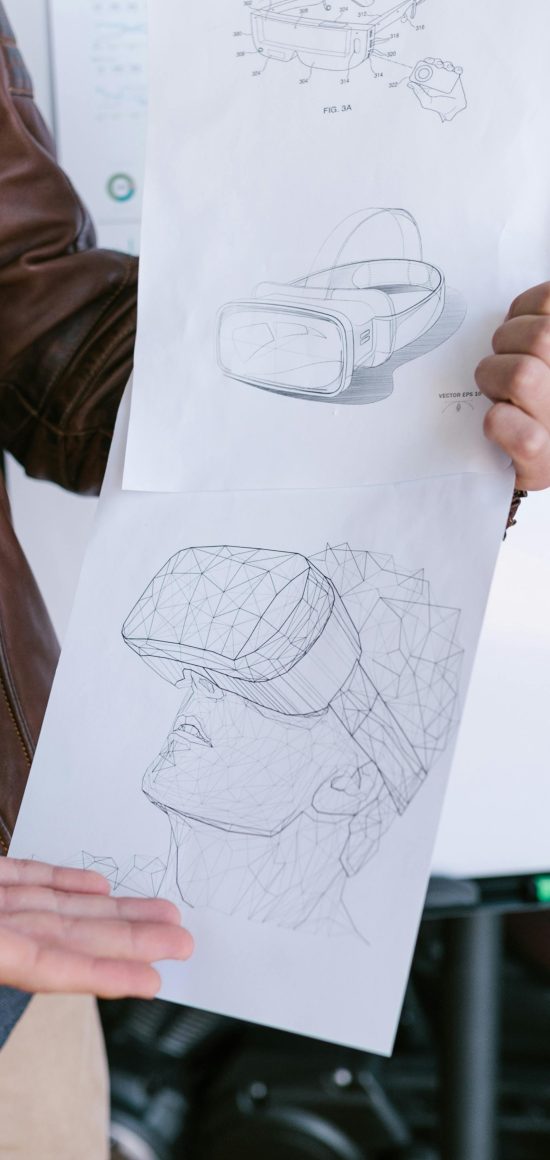 Close-up of VR headset design sketches held by a person showcasing innovative technology ideas.