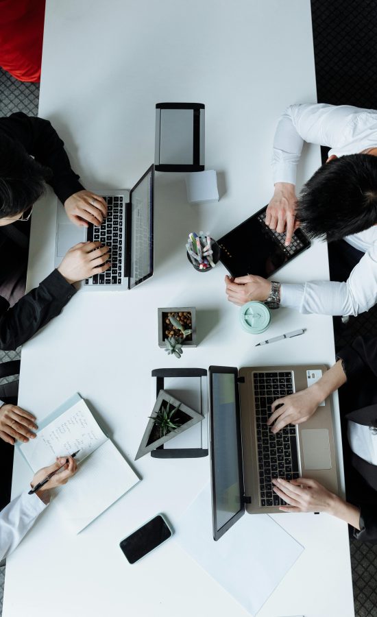 A diverse team working together in a modern office setting, focusing on laptops and collaboration.