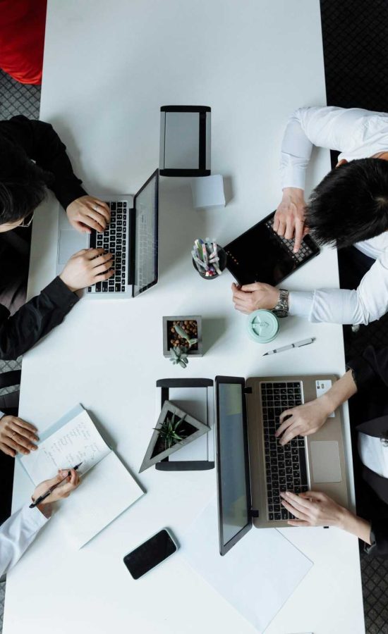 A diverse team working together in a modern office setting, focusing on laptops and collaboration.